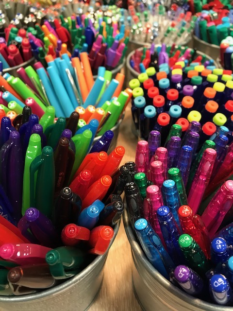 Des seaux remplis de stylos de toutes les couleurs, vus de dessus